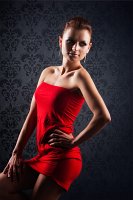 Halbkrperaufnahme stehend mit rotem Kleid vor dunklem Hintergrund